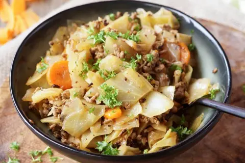 Herzhaftes Gericht aus spitzkohl mit hackfleisch und kartoffeln, garniert mit Petersilie.