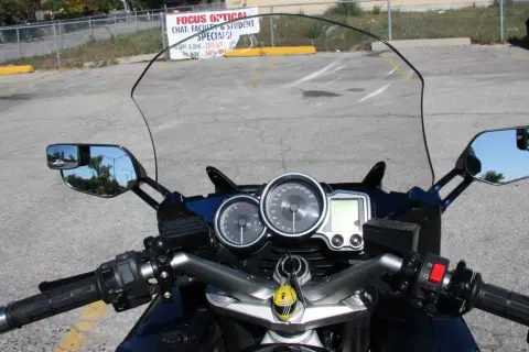Widok z motocykla: przedłużenie lusterek motocyklowych, deska rozdzielcza z prędkościomierzem i obrotomierzem.
