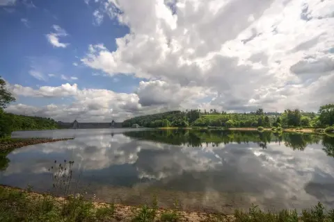 Stausee mit imposanter Staumauer, gespiegelt im ruhigen Wasser. Ein idyllischer Anblick, seen in NRW.