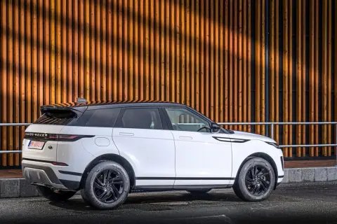 Weißer Range Rover Evoque 2.0 Diesel, moderne Optik vor Holzfassade. Gute Range Rover Evoque 2.0 Diesel Erfahrungen gesucht?