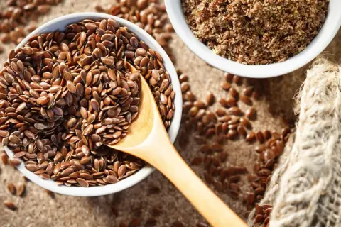 Schüssel mit ganzen Leinsamen und gemahlenen Leinsamen. Leinsamen roh essen ist gesund!