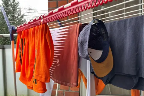 Wäscheleine mit Kleidung, darunter eine orangefarbene Sportbekleidung und eine Kappe zum Reinigen.