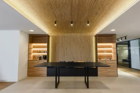 Modern office interior with a wall covered in vertical wood slats, demonstrating como poner listones de madera en la pared.