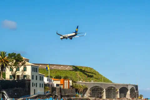 Samolot Ryanair ląduje na lotnisku na Maderze, nad budynkami i basenem z delfinem.