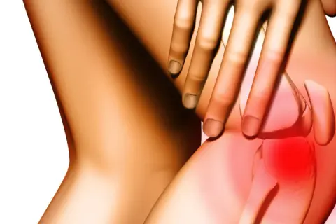 Dłoń uciska bolące kolano, gdzie widoczny jest nadziąślak. Czerwony obszar wskazuje na stan zapalny.