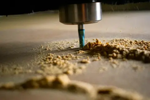 Narzędzie CNC obrabia drewno, tworząc wióry. Optymalne parametry skrawania zapewniają precyzję i wydajność.