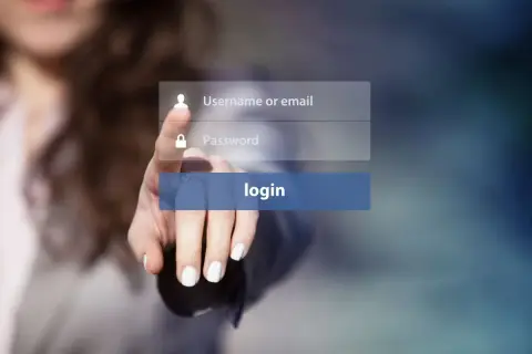 Dłoń naciska przycisk logowania. Widoczne pola na username i hasło, sugerujące proces uwierzytelniania.