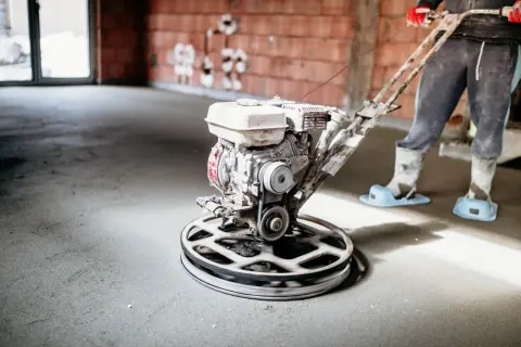 Pracownik wygładza posadzkę mechanicznie. Sprawdź, jaka jest styrobeton cena za m2 dla Twojego projektu budowlanego.