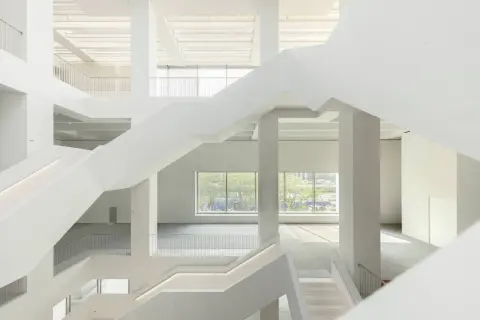 Wnętrze nowego muzeum sztuki nowoczesnej w Warszawie. Białe, geometryczne schody i przestrzenie tworzą nowoczesną architekturę.