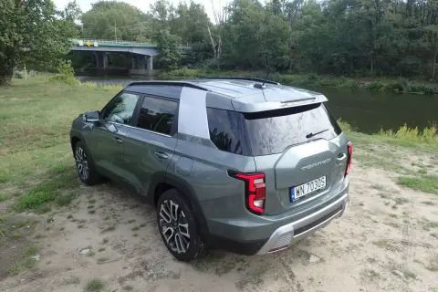 Zielony Torres auto zaparkowany nad rzeką, w tle most i las.