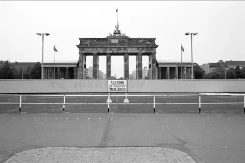 Brama Brandenburska z tablicą "ACHTUNG Sie verlassen jetzt West-Berlin", symbolizująca czas, kiedy powstał mur berliński.