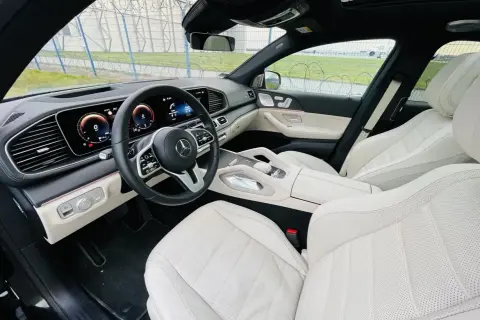 Wnętrze luksusowego Mercedesa GLE 400d z jasną, skórzaną tapicerką i nowoczesnym kokpitem.