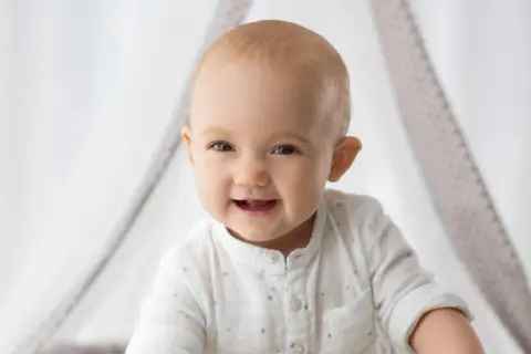 Ein strahlendes Babygesicht, das neugierig in die Welt blickt. So ähnlich sehen Babys mit 1 Woche, wenn sie ihre Umgebung erkunden.