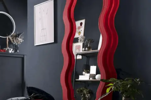 Ozdobne lustro z falowaną, czerwoną ramą. Dowiedz się, jak powiesić lustro z ramą, by stworzyć stylowe wnętrze.