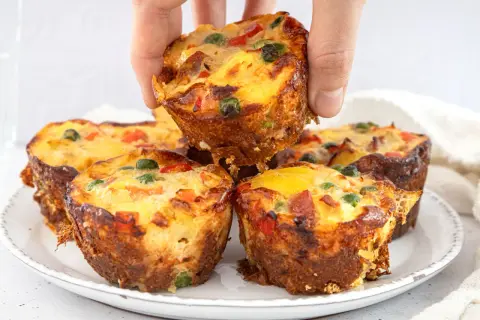 Goldbraune, herzhafte Pizza Muffins mit bunten Gemüsestückchen und Käse, die gerade aus dem Ofen kommen.