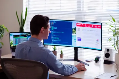Uomo al lavoro, con la sua postazione schermo PC ottimale per la produttività.