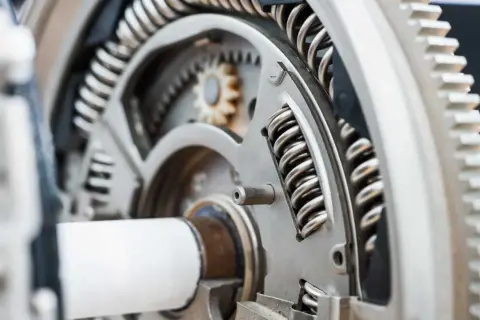 Mechanizm z zębatkami i sprężynami, element dociskowy w przekładni.