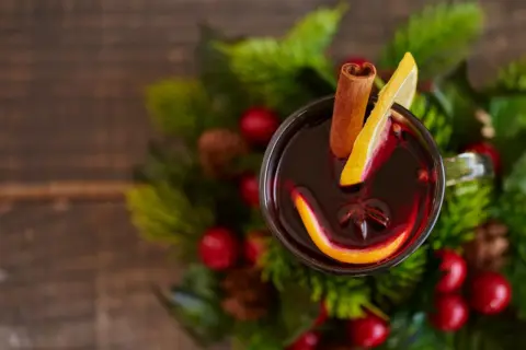Glogg przepis: aromatyczny grzaniec z pomarańczą, cytryną i cynamonem, otoczony świątecznymi gałązkami.