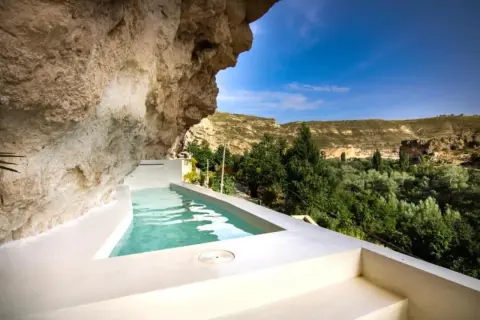 Piscina privada en cueva, ideal para una escapada fin de semana cerca de Madrid. Disfruta del paisaje verde y el cielo azul.
