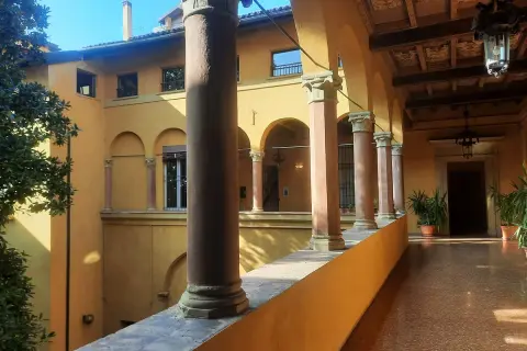 Portico con colonne e archi, tipico della casa di Lucio dalla a Bologna. Luce solare illumina il pavimento lucido.