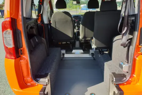 Interno di un Fiat Qubo arancione, con sedili posteriori e ampio spazio per il bagagliaio. Le dimensioni del bagagliaio sono ideali per trasporti.