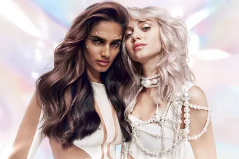 Deux femmes aux cheveux magnifiques, l'une brune avec des reflets roses, l'autre blonde platine. Un avant-après de la coloration Dialight Clear, sublimant leur éclat.