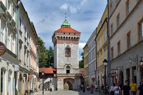 Brama Floriańska w Krakowie, majestatyczna wieża z czerwoną dachówką i kamienną fasadą, wita spacerowiczów.