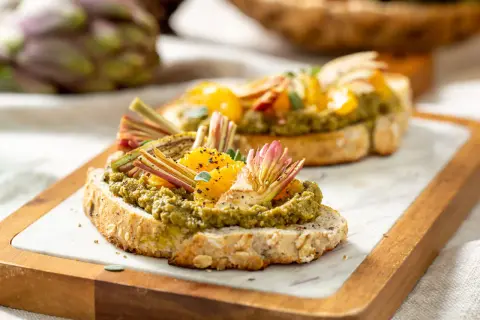 Deliziosi crostini con paté di carciofi, spicchi d'arancia e finocchietti croccanti su pane integrale tostato.