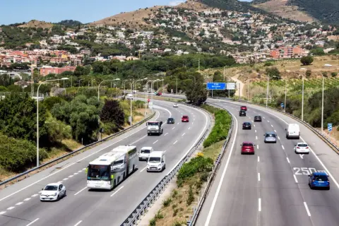 Voiture sur autoroute en Espagne, respectant la limitation vitesse espagne. Paysage vallonné avec des maisons en arrière-plan.