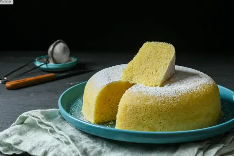 Delicioso bizcocho esponjoso, ideal para un mug cake yogur, espolvoreado con azúcar glas sobre un plato turquesa.
