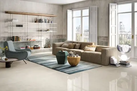 Salotto moderno con divano chevron, poltrona a zig-zag e scaffali bianchi. Pavimento in gres porcellanato color avorio.