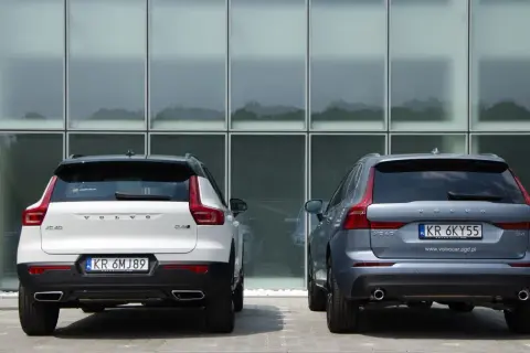 Dwa SUV-y Volvo: białe XC40 i szare XC60, stoją przed nowoczesnym budynkiem. Porównanie ich wymiarów jest łatwe.