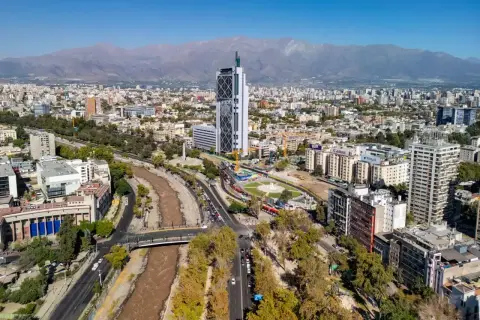 Widok na nowoczesną architekturę i rzekę w Santiago, stolicy Chile, z górami w tle.