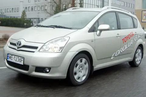 Srebrna Toyota Corolla Verso jedzie po mokrej drodze. Na drzwiach widnieje napis "Toyota Corolla Verso".