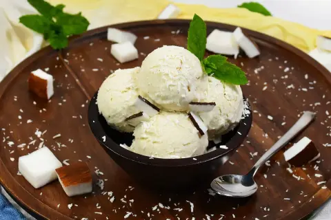 Schüssel mit Kokosnuss-Eis, garniert mit Kokosraspeln und Minze. Perfekt, um Kokosnuss Eis selber machen zu wollen!