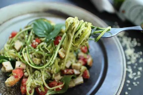 Délicieuses pâtes aux légumes sautés, un plat coloré et sain avec des courgettes en spirales, des tomates cerises et du basilic frais.