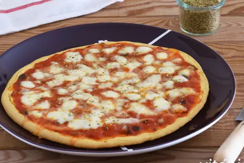 Pizza de garbanzos con queso derretido y salsa de tomate, lista para disfrutar.
