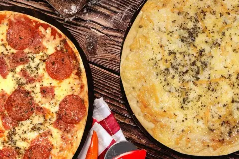 Dos pizzas recién horneadas, una de pepperoni y otra de queso, listas para disfrutar en la pizzeria Carboneras.