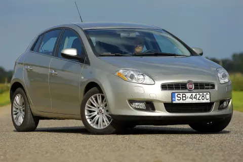 Srebrny Fiat Bravo 2 z wyraźnymi żarówkami reflektorów, zaparkowany na drodze.