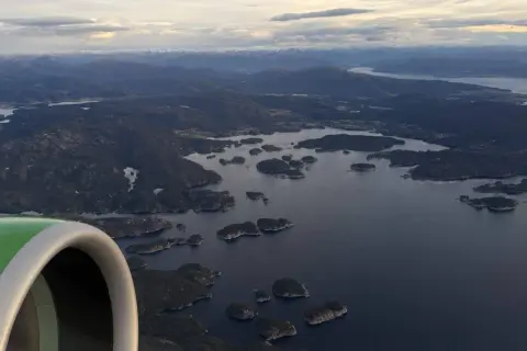 Flugzeugfenster mit Blick auf norwegische Schärenlandschaft. Gute Widerøe Airline Erfahrungen auf dieser Route.