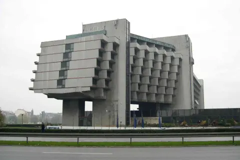 Monumentalny budynek w stylu brutalizm, z betonową fasadą i charakterystycznymi, wystającymi elementami.