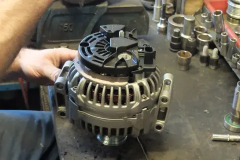 Warsztat samochodowy, gdzie mechanik sprawdza alternator. Zastanawiasz się, ile kosztuje regeneracja alternatora?