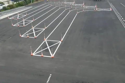 Plac manewrowy z pachołkami i białymi liniami, idealny do nauki, jak kręcić kierownicą podczas jazdy po łuku.
