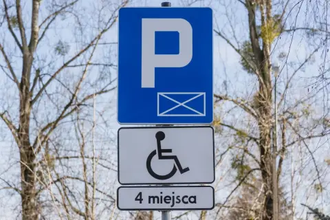 Znak P z kopertą i symbolem wózka inwalidzkiego, informujący o 4 miejscach parkingowych dla niepełnosprawnych.