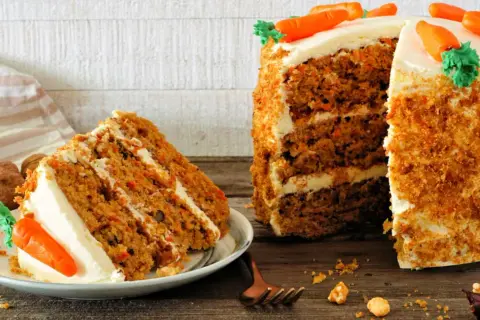 Delicioso carrot cake receta original inglesa, con capas de bizcocho y crema, decorado con zanahorias de mazapán.