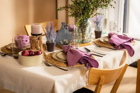 Elegancka, codzienna dekoracja stołu w salonie z fioletowymi serwetkami, świecą i lawendą.