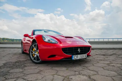 Czerwone Ferrari California z żółtymi zaciskami hamulcowymi na tle błękitnego nieba z chmurami.