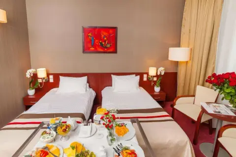 Pokój hotelowy z dwoma łóżkami, śniadaniem na tacy i bukietem róż. Idealne miejsce na pobyt, zgodnie z premier kraków hotel opinie.