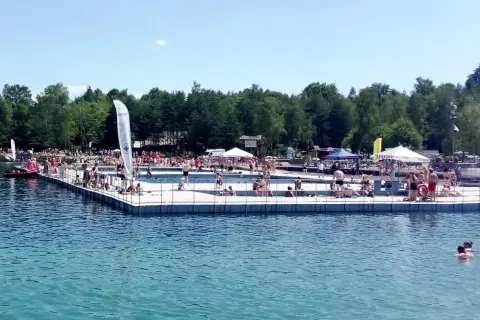 Słoneczny dzień nad wodą w Balatonie Trzebinia. Ludzie odpoczywają na pomoście i kąpią się w jeziorze.