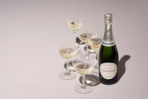 Laurent-Perrier Champagnerflasche mit gefüllten Gläsern. Die Dosage Champagner Bedeutung liegt in der perfekten Balance.